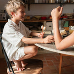 A child playing with the 2 Grapat wooden twin soul puppets by a table