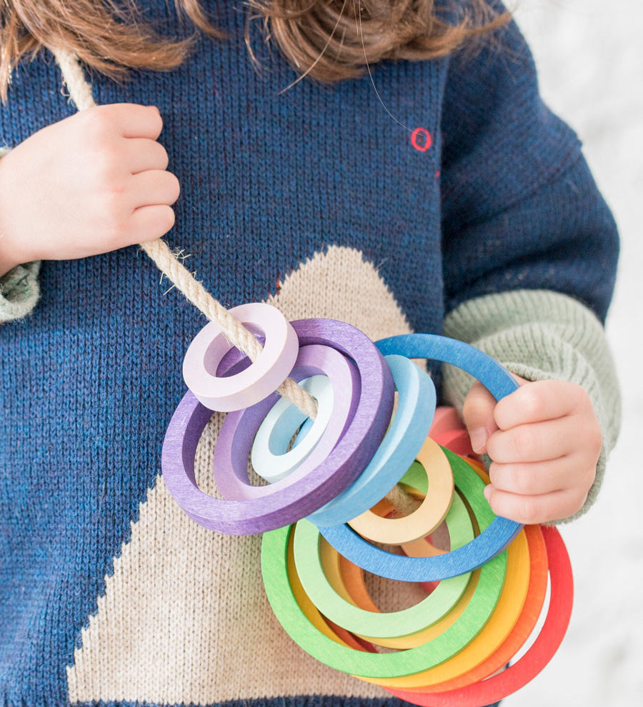 A child with the Grapat Wooden Nesting Rings strung on a rope. 