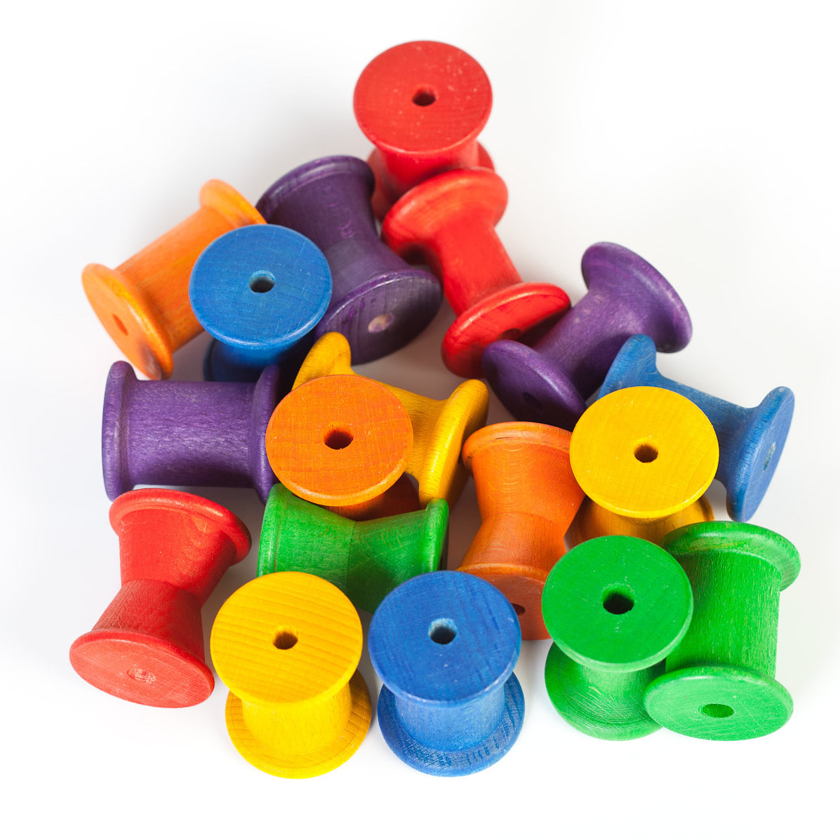 colour match and count with these rainbow coloured wooden toy reels. Mixed colours stacked on a white background.