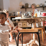 A child playing with the Grapat wooden twin soul puppets by a chair