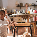 A child playing with the Grapat wooden twin soul puppets by a chair