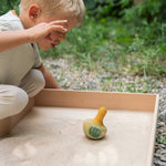 A child playing with the Grapat wooden yellow flowing bird outside in a sandpit 