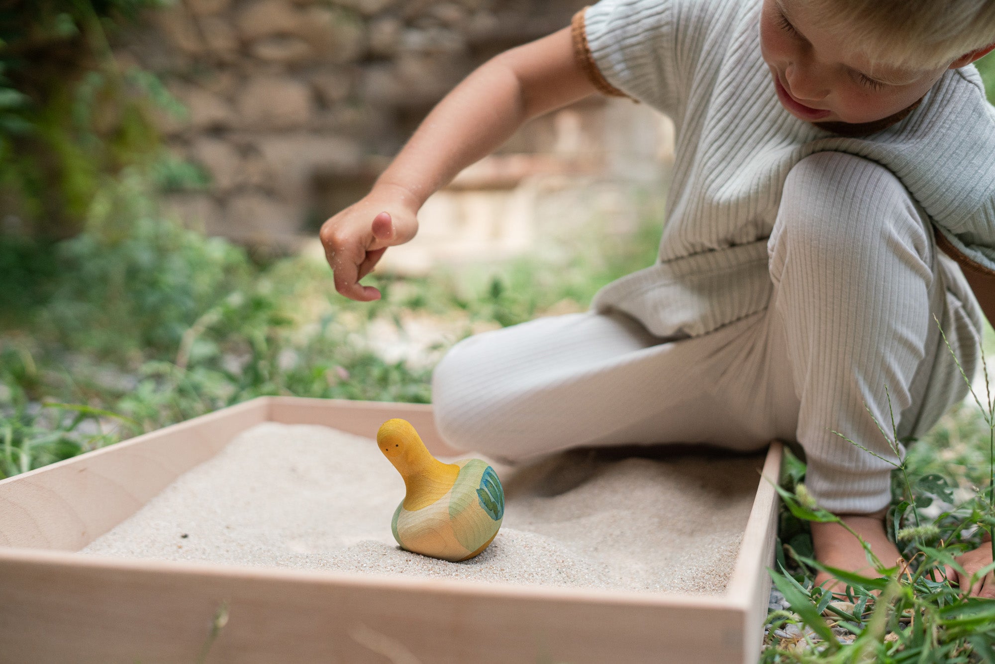 A child playing with the Grapat wooden yellow flowing bird outside 