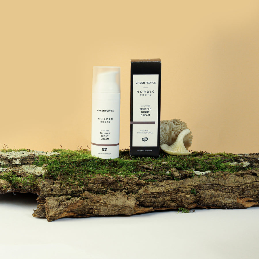 Green People Nordic Roots Truffle Night Cream pictured next to the box placed on a moss covered branch