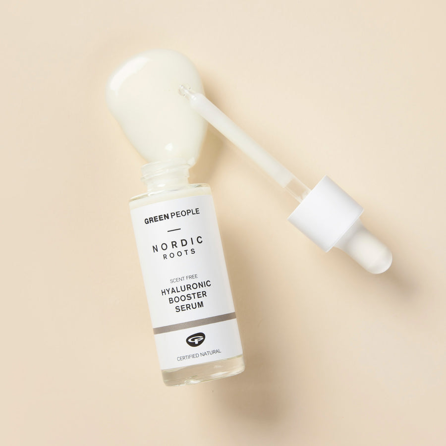 Green People Nordic Roots Hyaluronic Booster Serum pictured open with product spilled on a cream coloured surface with the pipette placed next to it