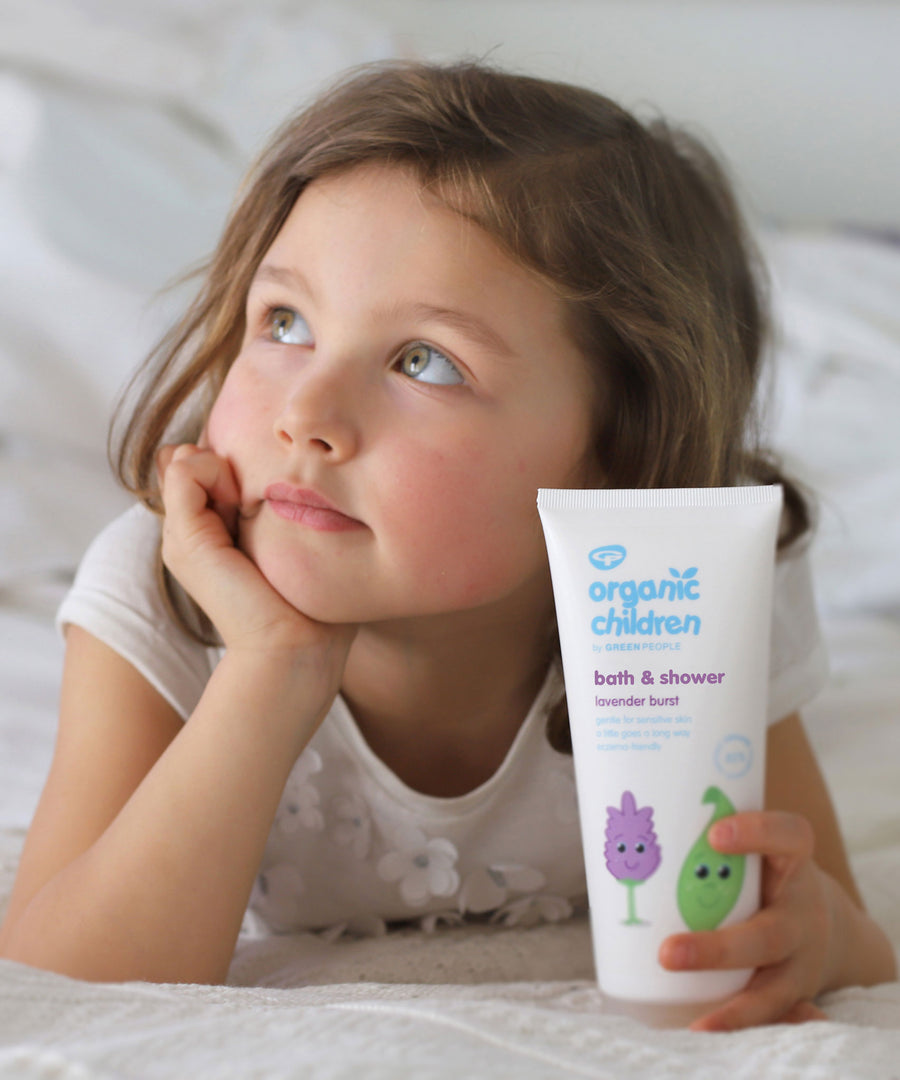 A child holding a tube of Organic Children Bath & Shower Gel Lavender Burst. 