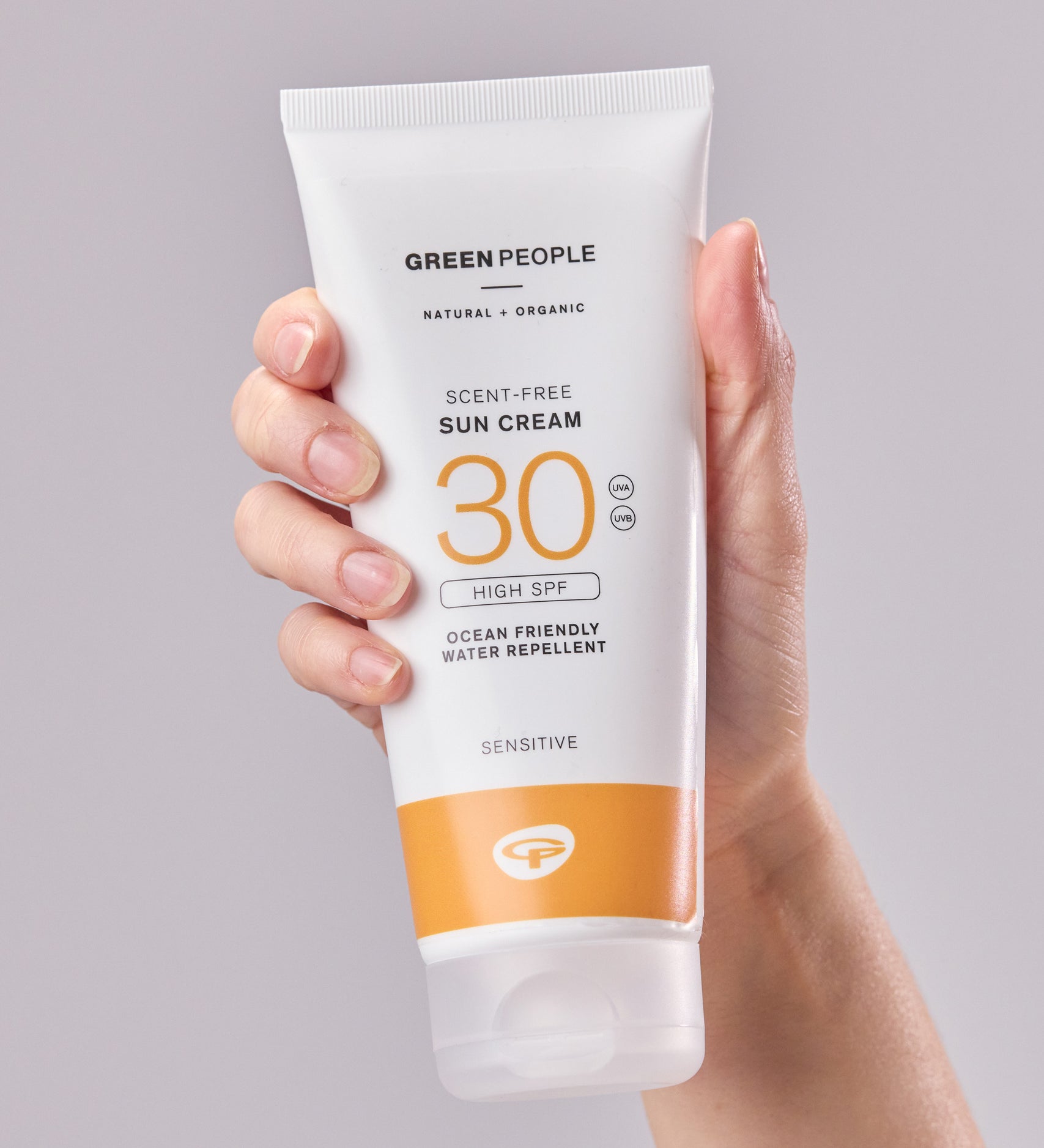 A tube of Green People Sun Cream SPF30 in an adult's hand. 