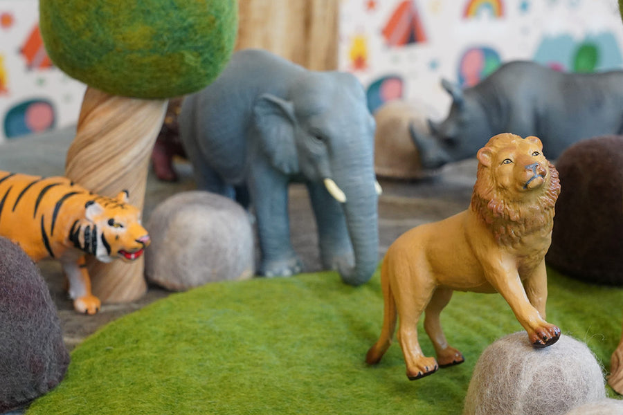 Green rubber toys eco-friendly lion figure perched on a papoose rock in front of a green rubber toys tiger and elephant