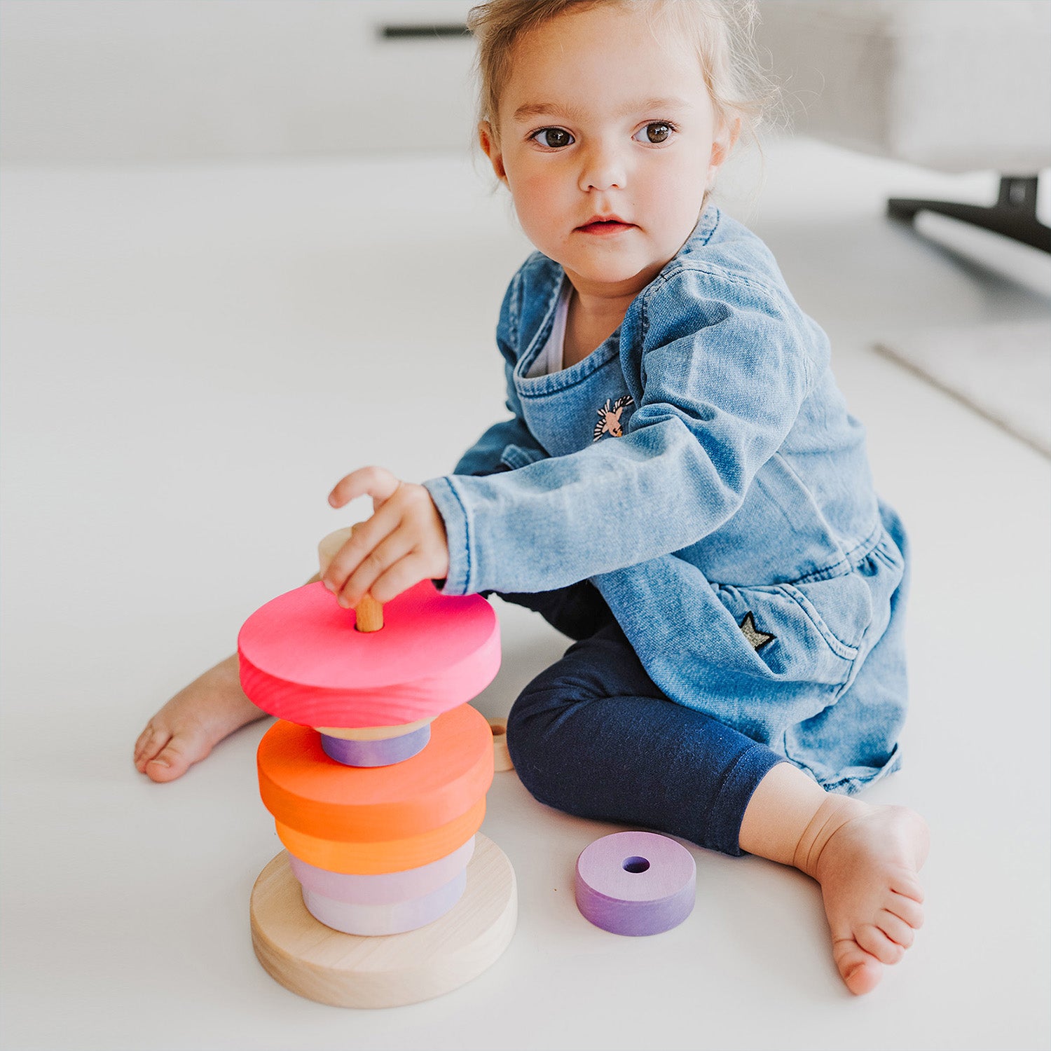 Grimm's Conical Stacking Tower - Neon Pink - A child plays alone with the stacking toy.