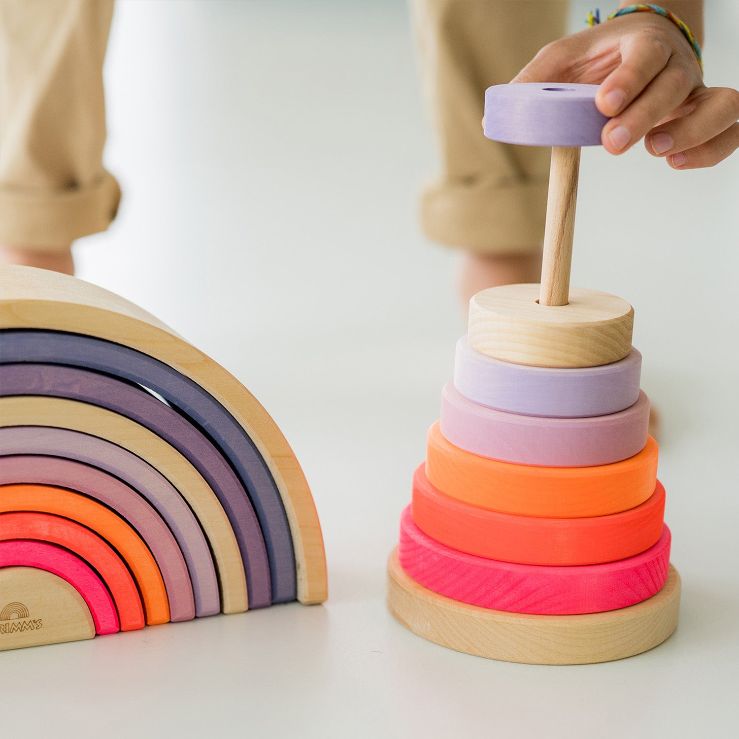 Grimm's Conical Stacking Tower - Neon Pink - On a plain blue background. Alternative puzzle layout. There are various Grimm's wooden blocks and figures in the background.