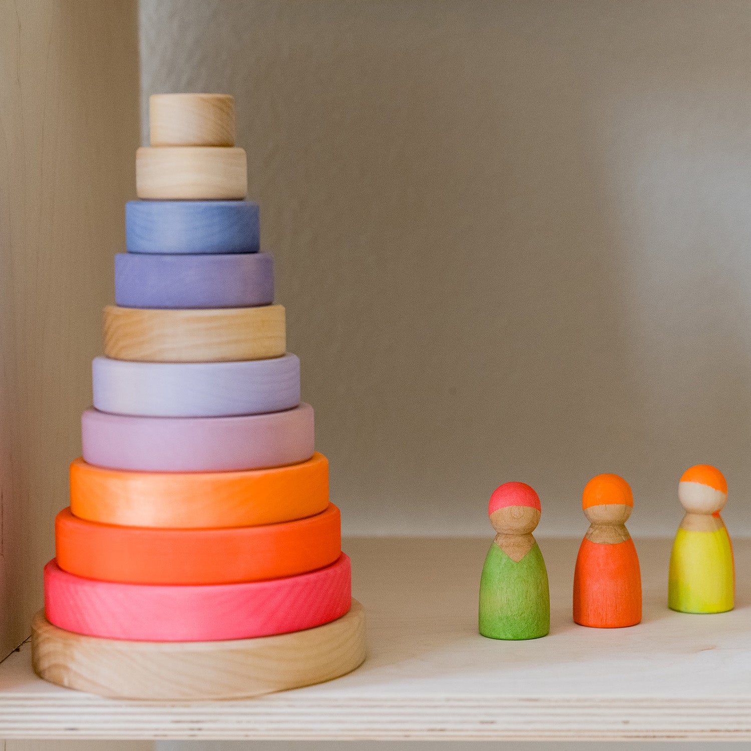 Grimm's Small Conical Stacking Tower and Grimm's Conical Stacking Tower - Neon Pink - Sit next to one another on a kitchen worktop. There is a vase in the background.