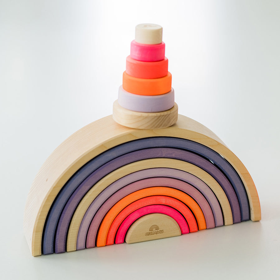 Grimm's Small Conical Stacking Tower - Neon Pink - On a plain blue background. Grimm's Neon Mix Friends are in front and on top of the Tower.