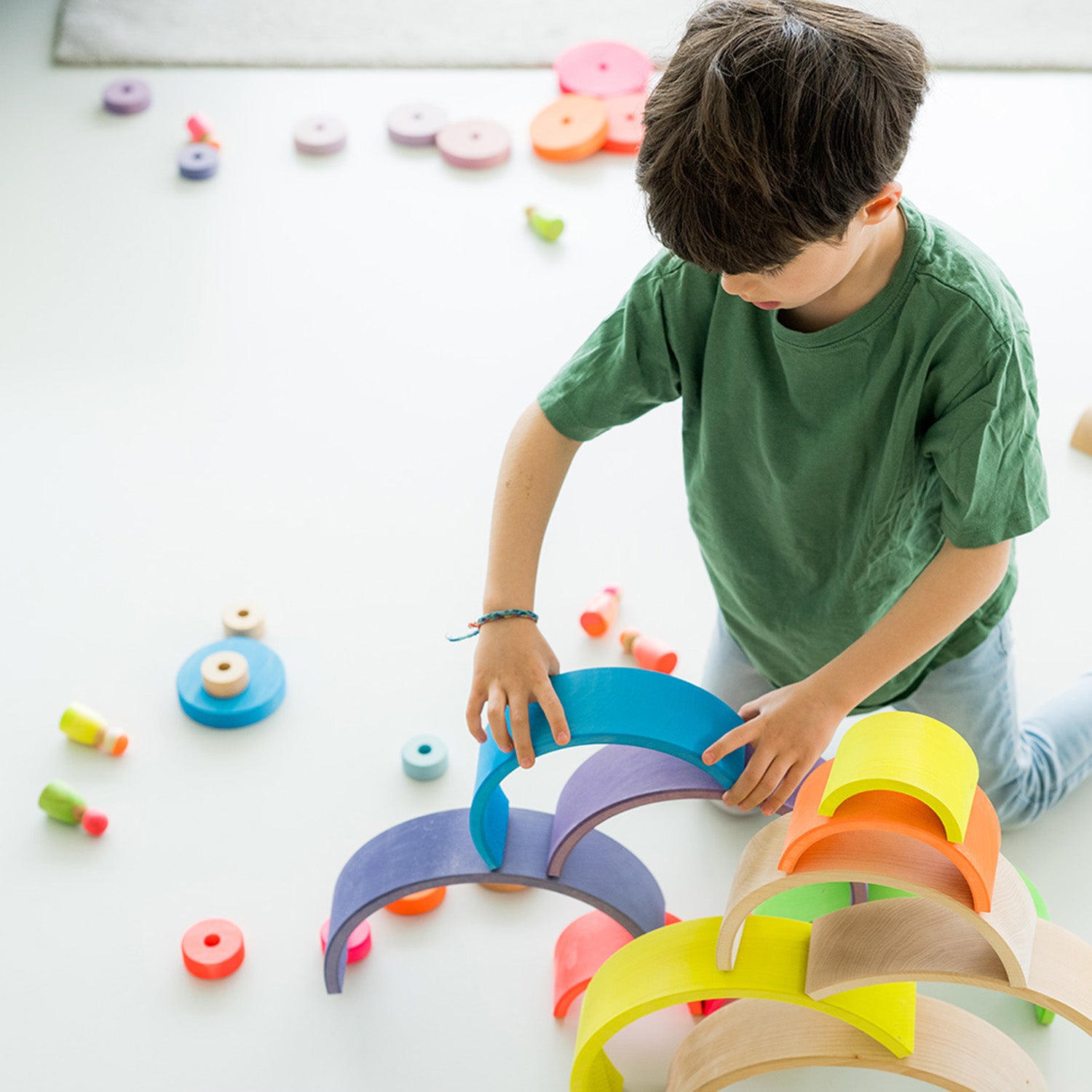 Grimm's Small Conical Stacking Tower - Neon Pink -A child plays in his house with several sets of Grimm's Rainbows