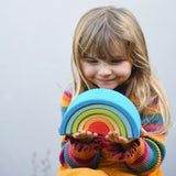 A child holding the Grimm's Babi Gwawr Sunrise 6 Piece Rainbow in their hands. 