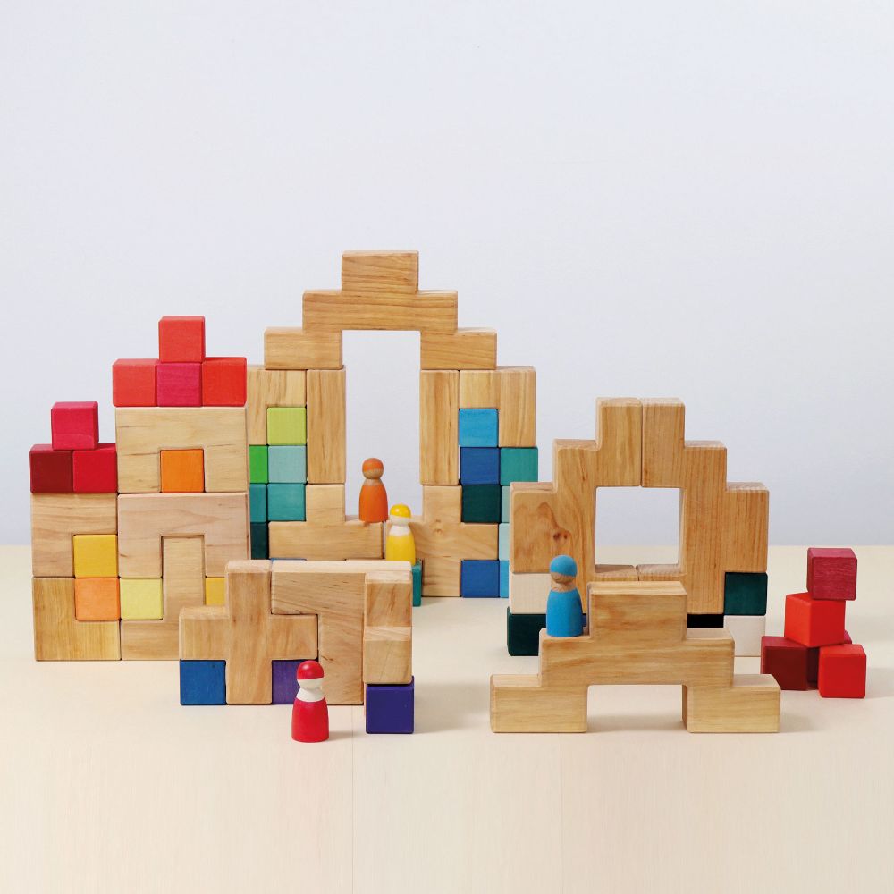 The Grimm's Natural Wooden Stairway Building Set built up with rainbow coloured cubes and Grimm's friends placed on the structure. 