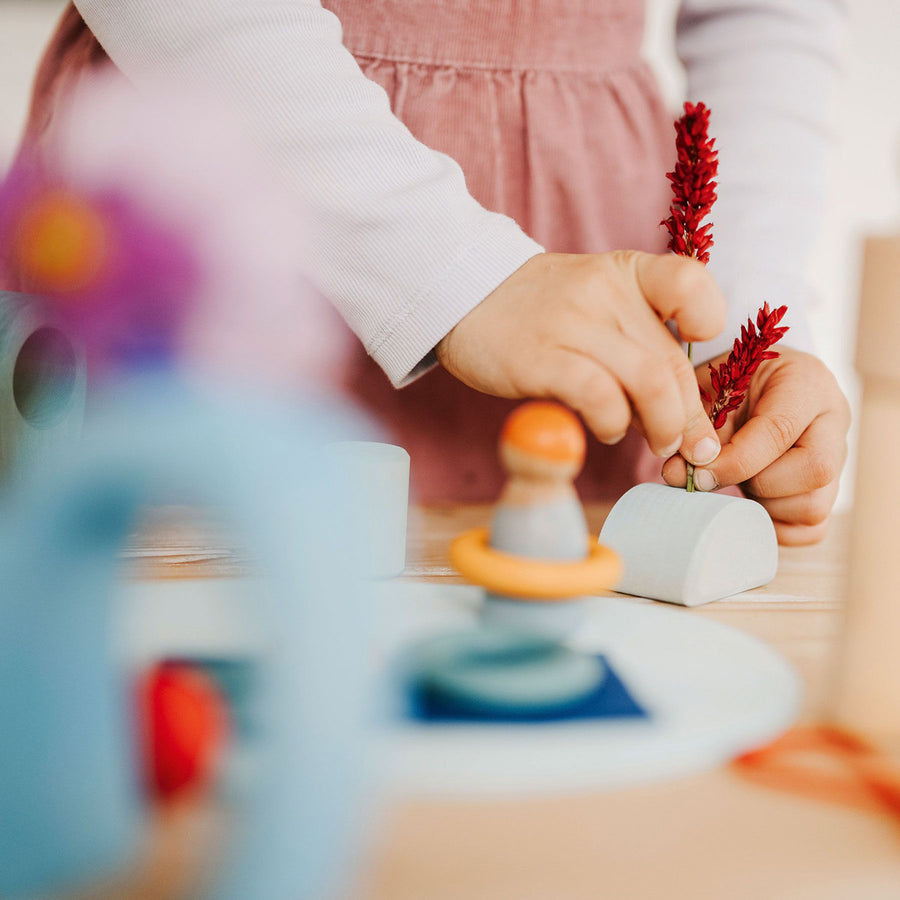 Close up of some hands building with the Grimm's plastic-free wooden toy blocks on a wooden table