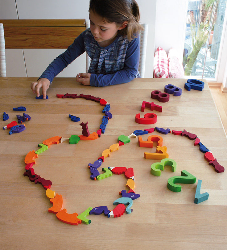 A child playing with the Grimm's Figures For Counting & Story Telling on a wooden table. 