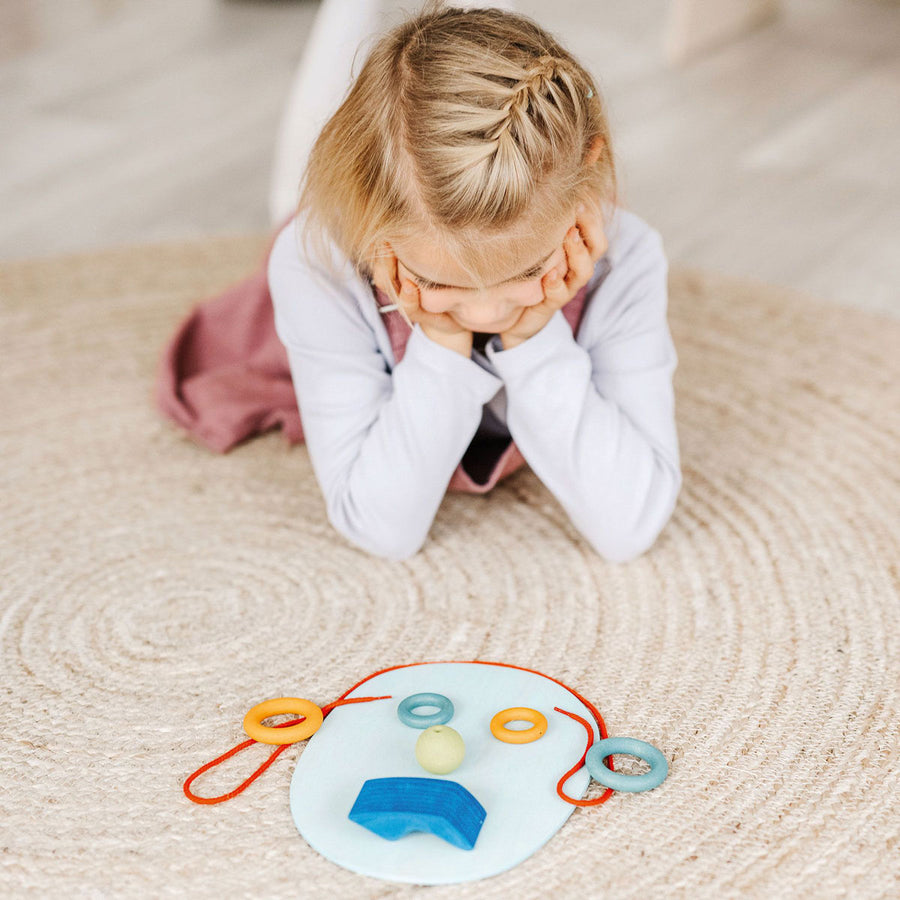 Young girl playing with some flowers and the Grimm's plastic-free wooden Waldorf toy blocks