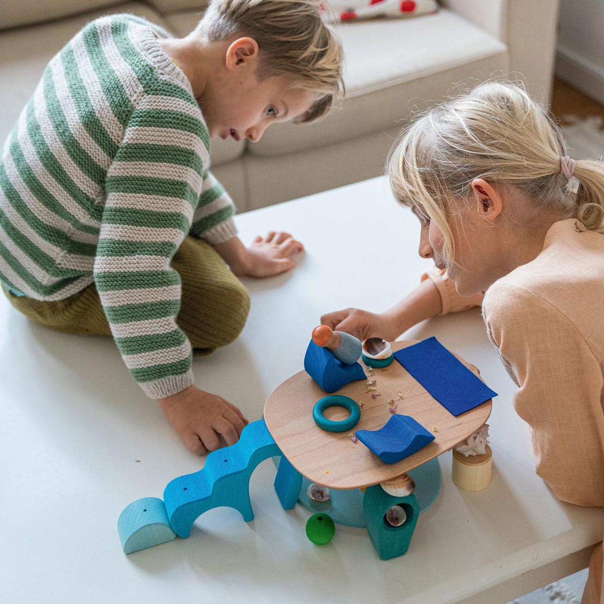 Close up of some hands building with the Grimm's plastic-free wooden toy blocks on a wooden table