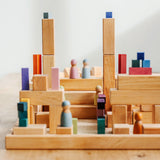 Grimm's large stepped pyramid Waldorf toy blocks stacked into a tower on a grey wooden floor