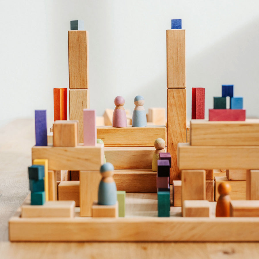 Grimm's large stepped pyramid Waldorf toy blocks stacked into a tower on a grey wooden floor