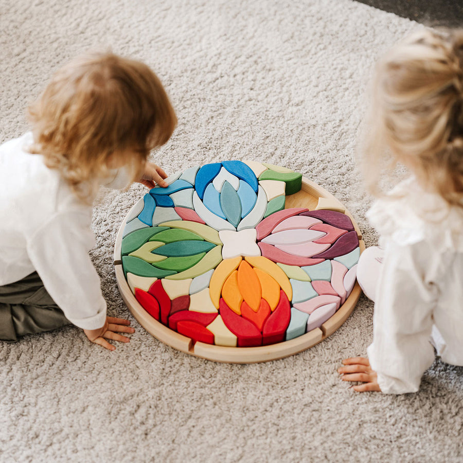 2 children sat on the floor next to the Waldorf wooden Lara mandala building blocks