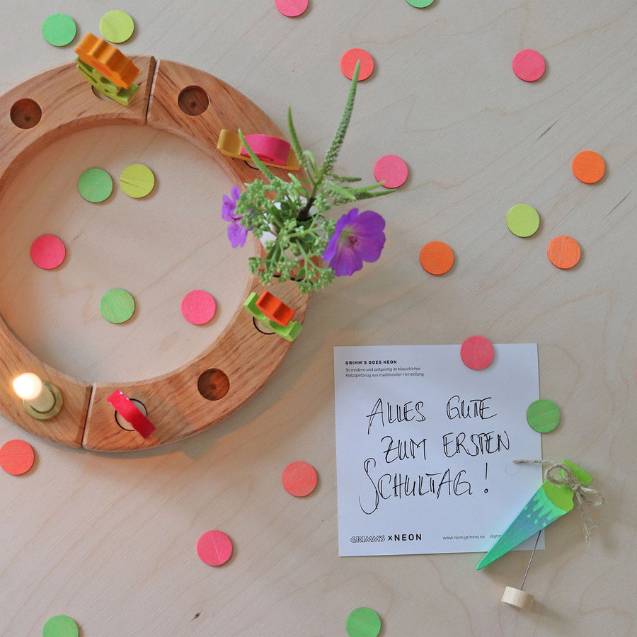 Grimm's Neon Celebration Confetti Dots. The dots surround a celebration ring on a wooden table.