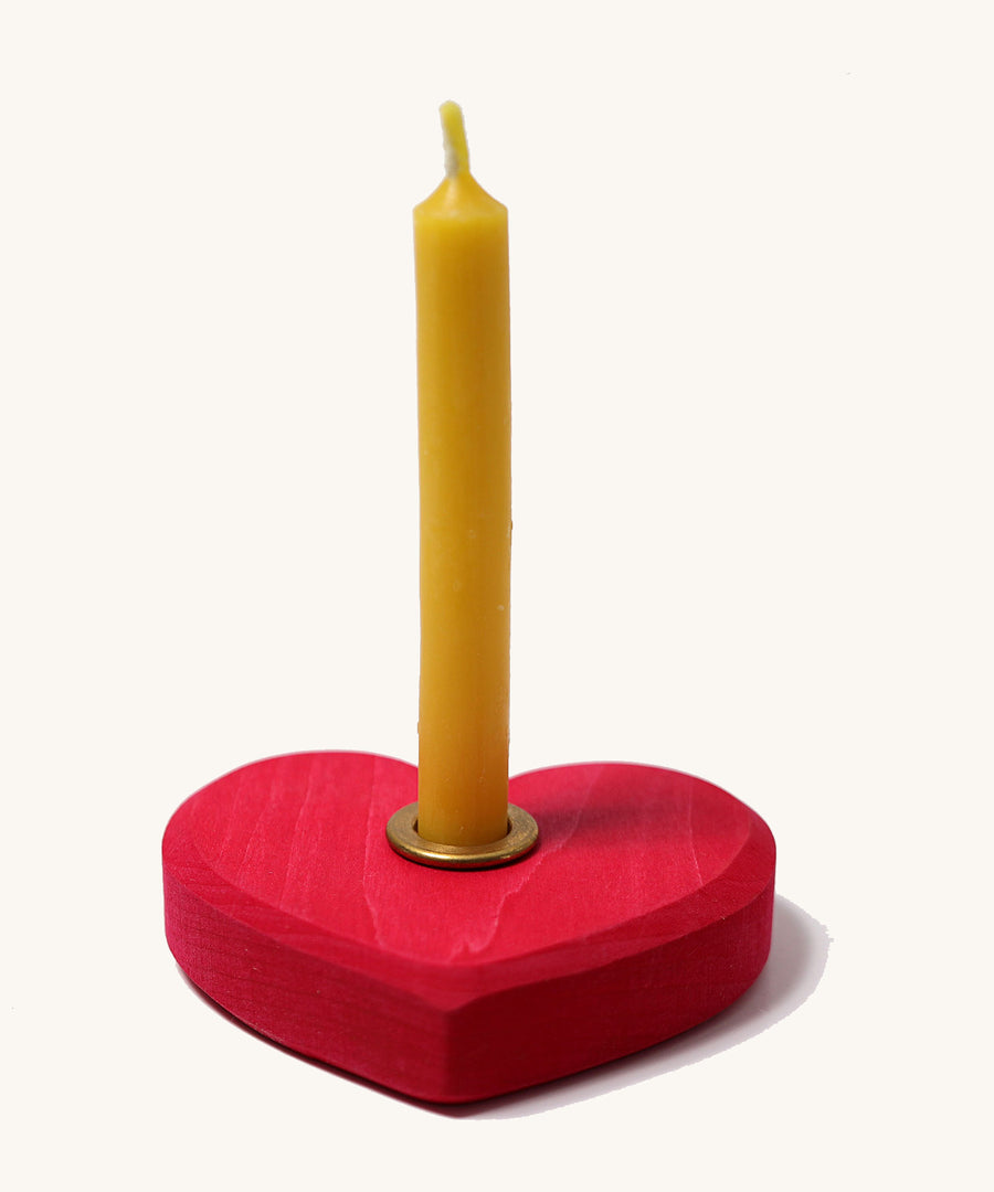 Grimm's Small Red Heart with a brass candle holder and candle on a plain background. 