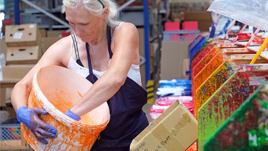 Worker in the Grimm's toys factory dipping toy piece in paint colour