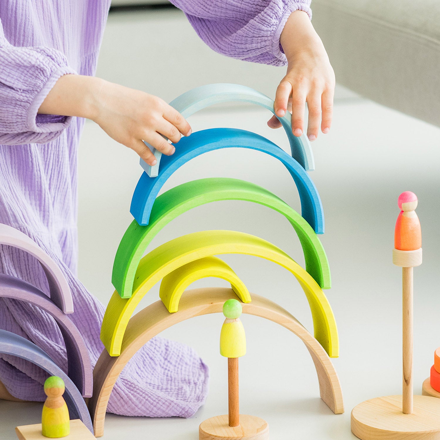 Grimm's 10-Piece Rainbow - Neon Green. A child plays in her house with the Rainbow