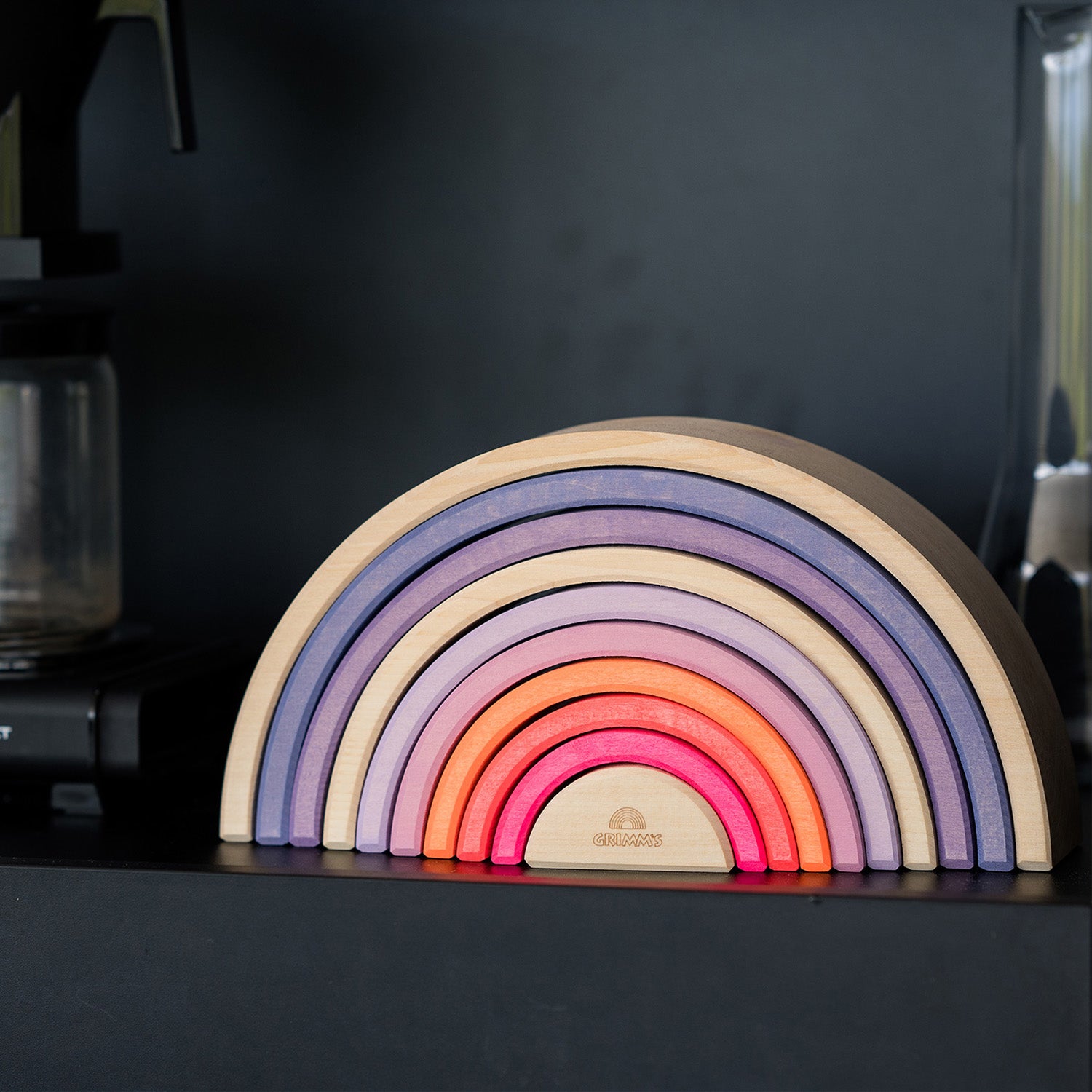 Grimm's 10-Piece Rainbow - Neon Pink- There are several sets of Grimm's Neon friends sitting on top of singular rainbow pieces.