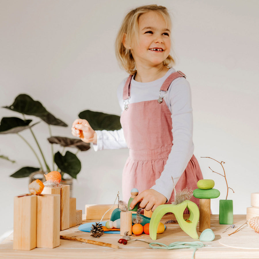 Grimm's plastic-free wooden toy blocks stacked in a tower on a wooden worktop