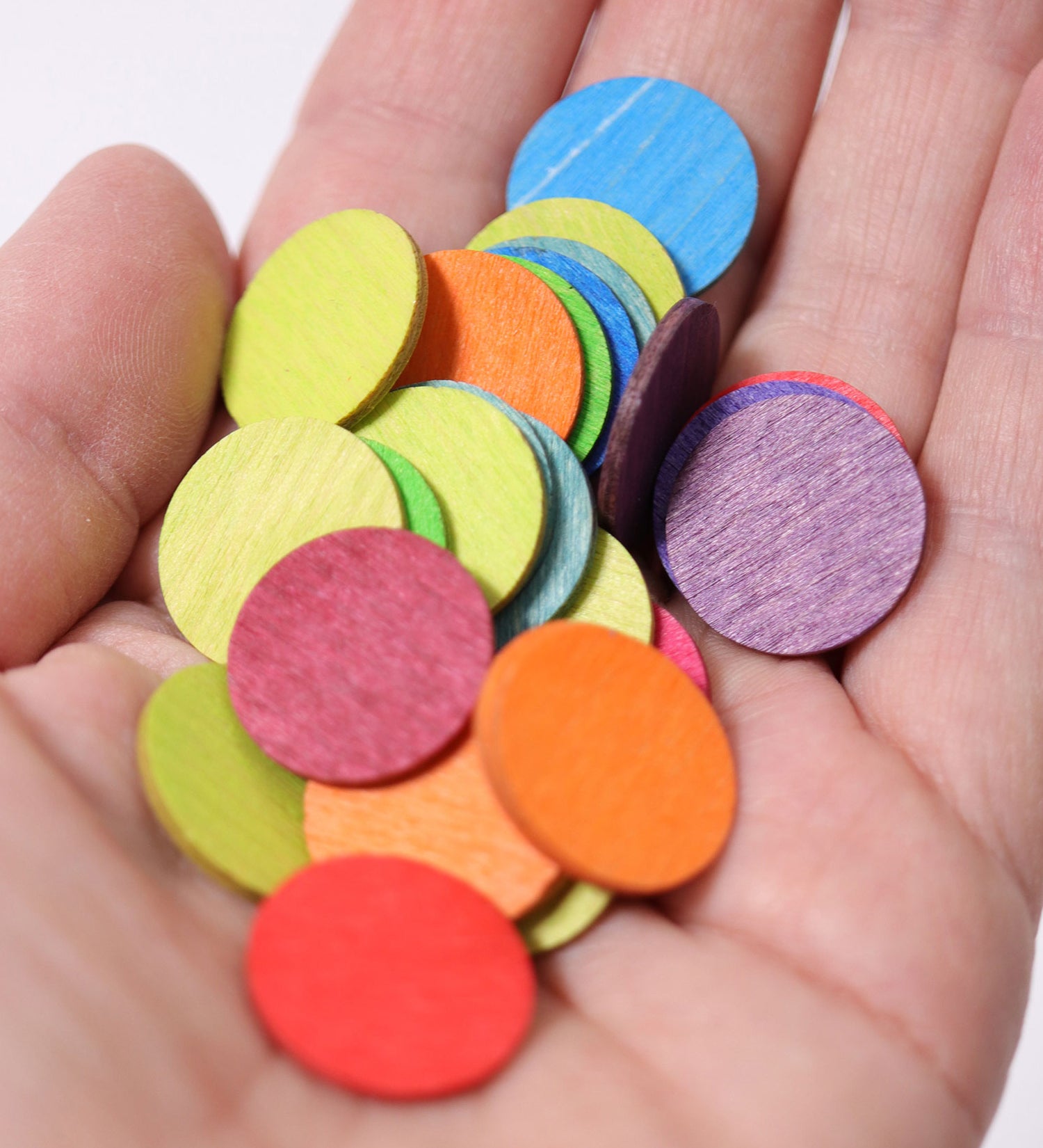 A close up of some Grimm's Rainbow Confetti Dots in an adult's hand. 