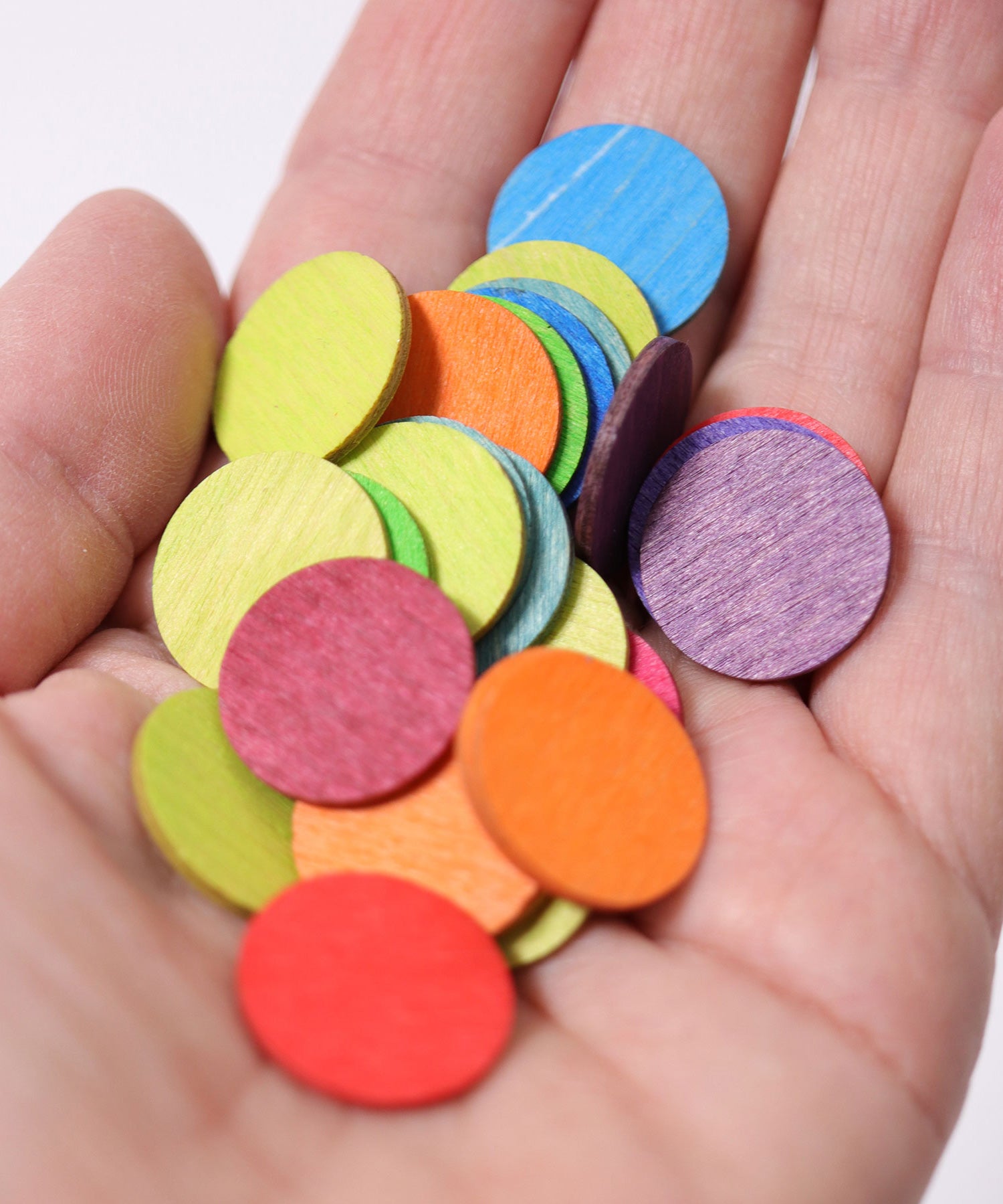 A close up of some Grimm's Rainbow Confetti Dots in an adult's hand. 