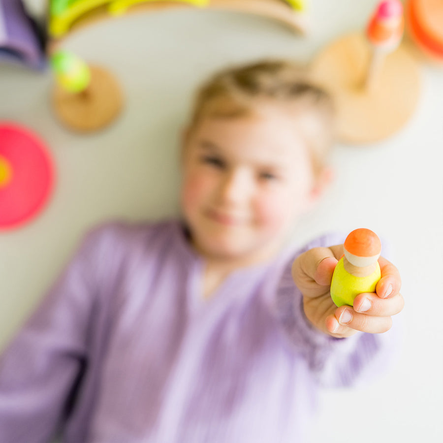 orange yellow and green being played with by a child with the Neon Green rainbow and Neon Pink stacking tower.