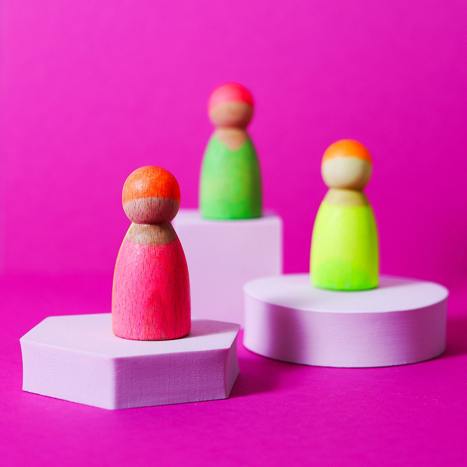 orange yellow and green being played with by a child in a green t-shirt with the Neon Green rainbow and Neon Pink stacking tower.