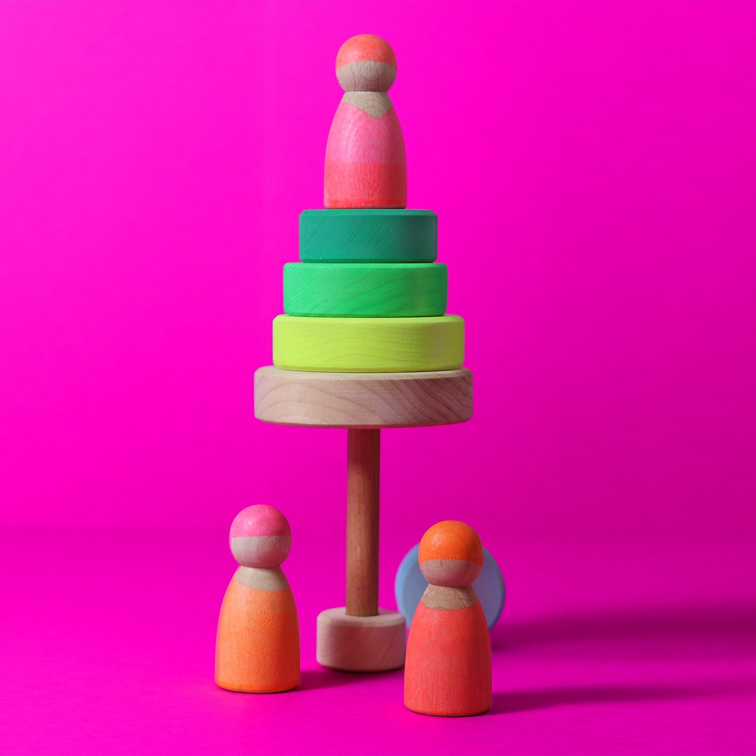 Grimm's Friends - Neon Pink - In a home environment. A child plays with a peg doll that is on top of a Neon Pink Stacker Tower.