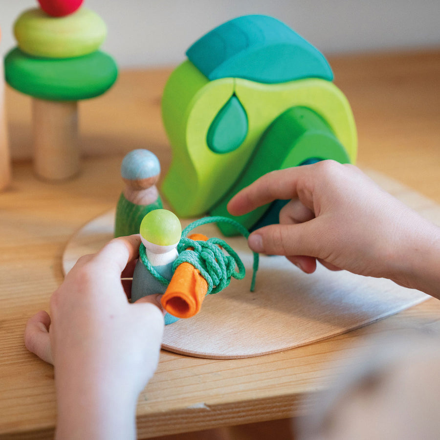 Girl smiling and playing with Grimm's Waldorf toy blocks on a wooden table