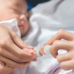 A close up view of the Haakaa nail file being used to file a baby's nail.