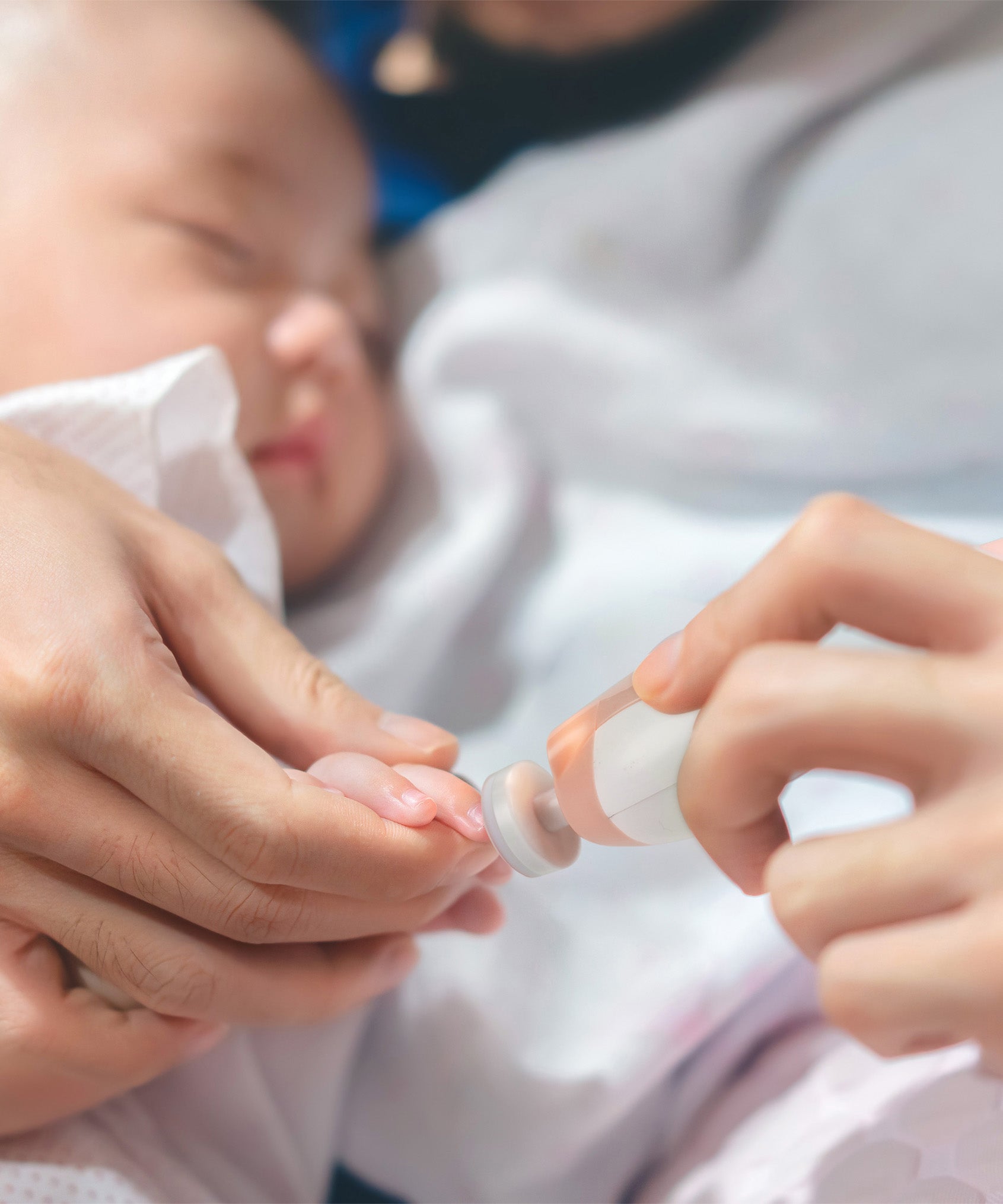 A close up view of the Haakaa nail file being used to file a baby's nail.