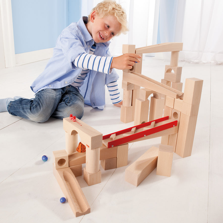 A child happily rolling blue marbles down the HABA Large Marble Run Track