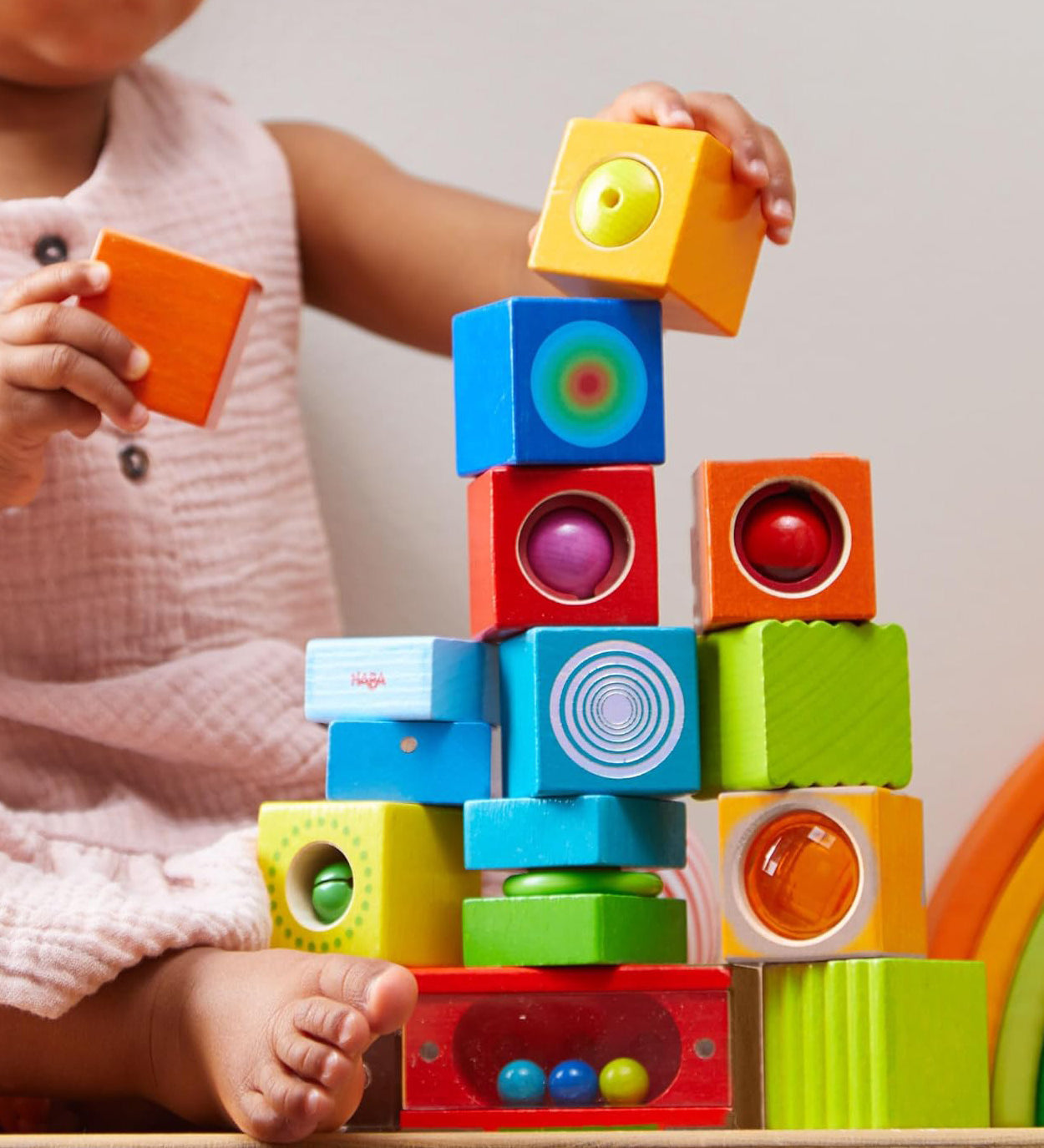 A child stacking the different coloured blocks from the Haba blocks with sounds set.