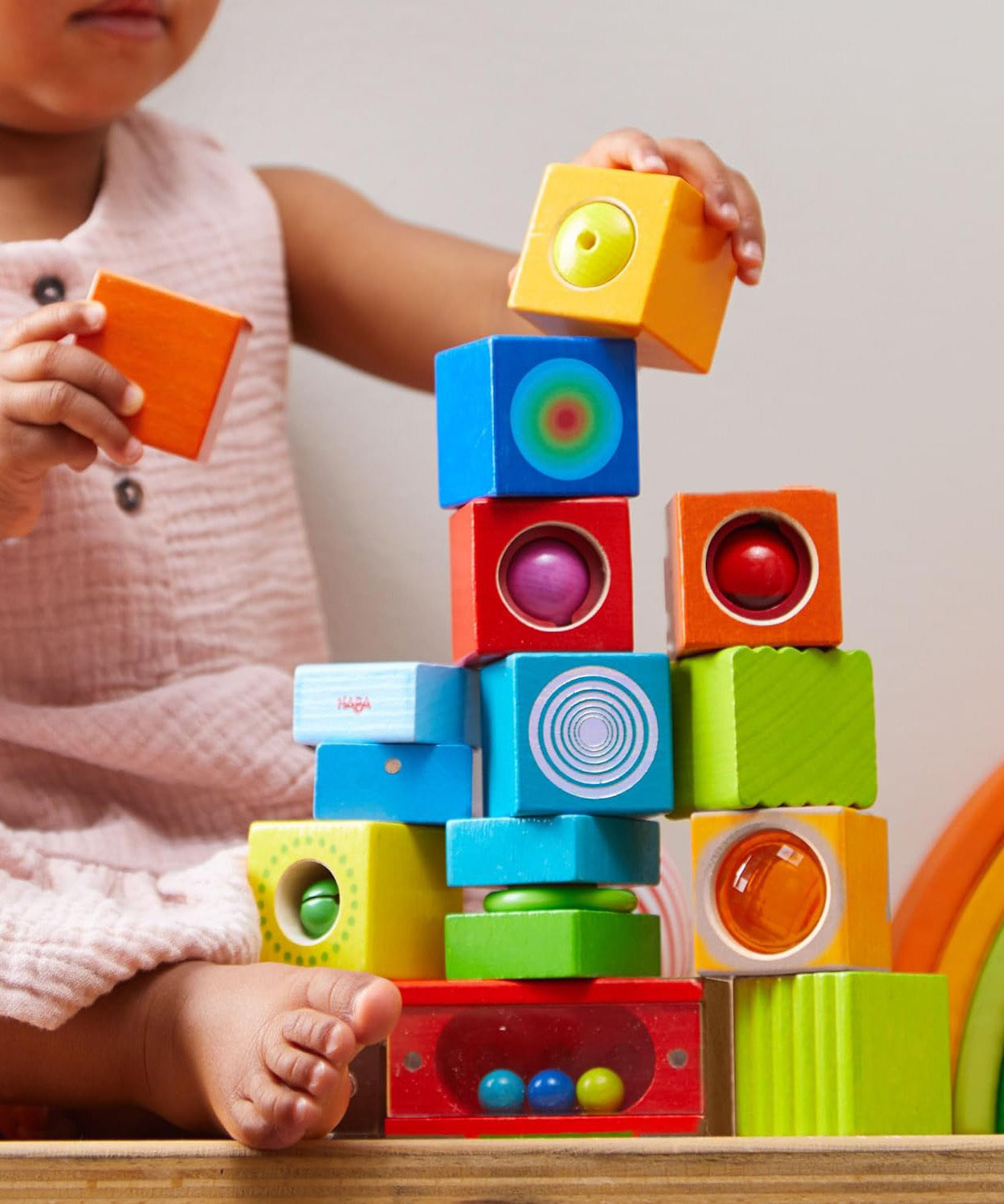 A child stacking the different coloured blocks from the Haba blocks with sounds set.