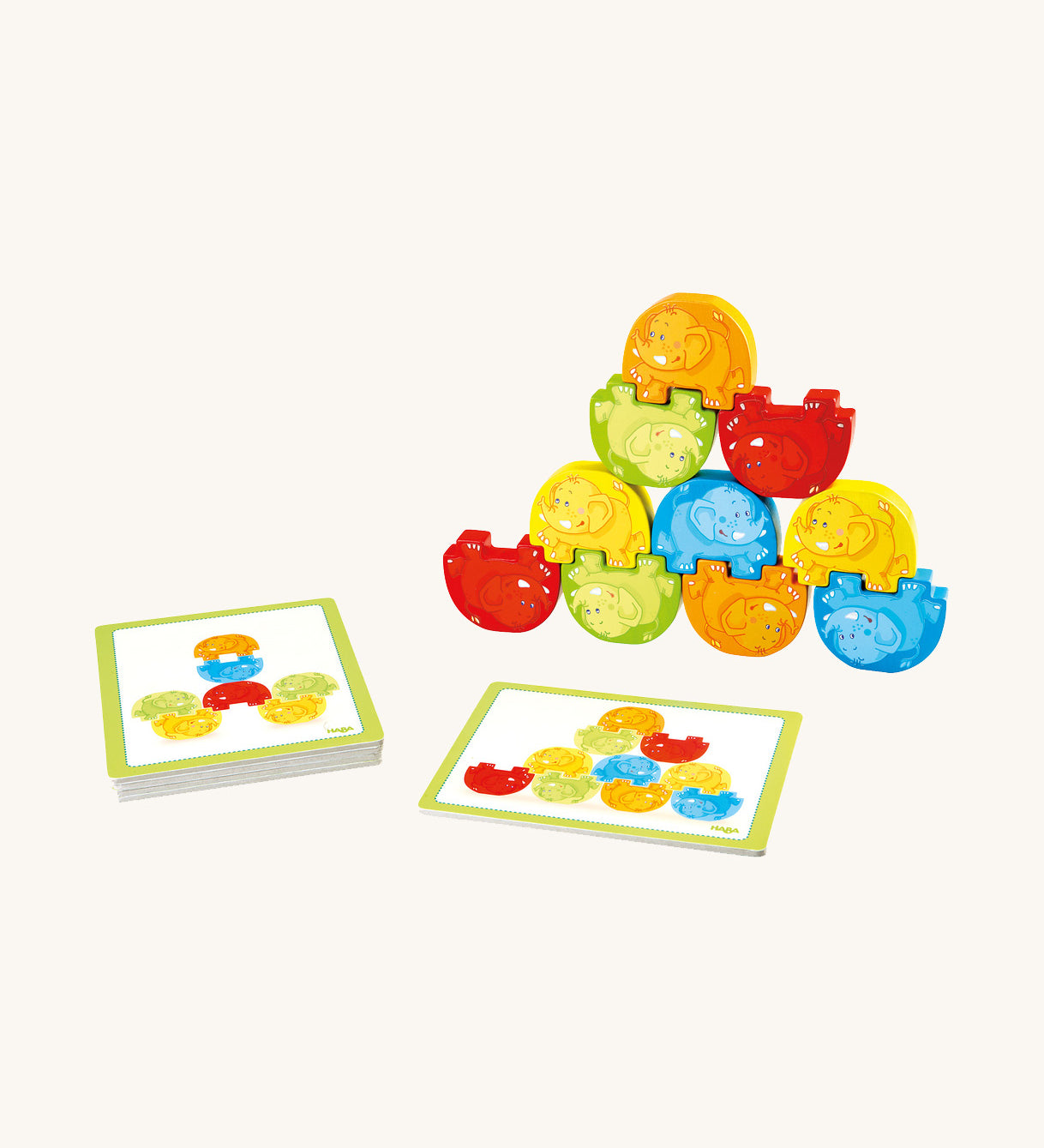 Red, yellow, green and orange wooden elephants from the Haba elephant stacking game stacked on top of each other with challenge card on a cream background. 