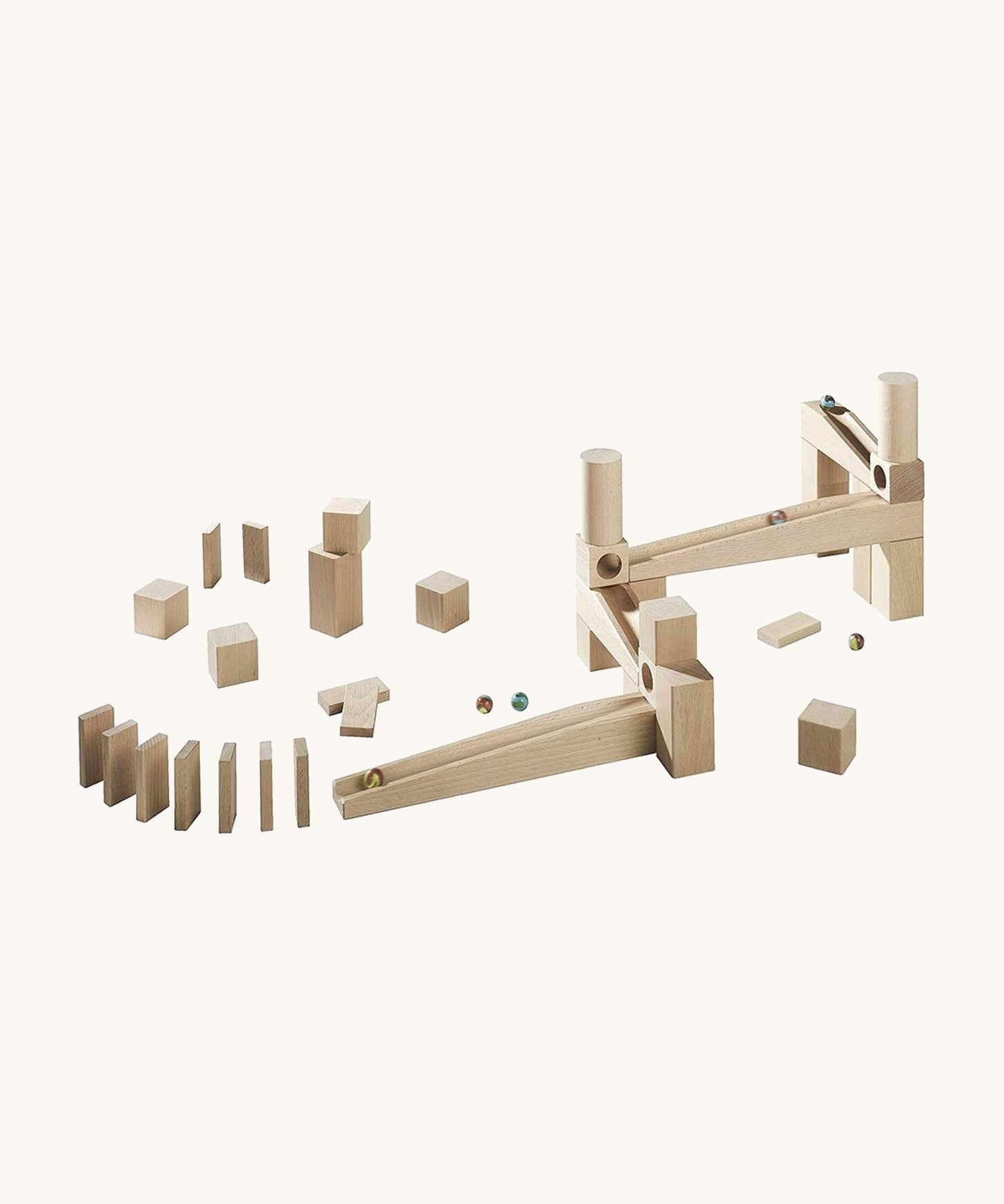 A a side angle of a marble run made from different natural wooden blocks from the Haba first playing blocks on a cream background.