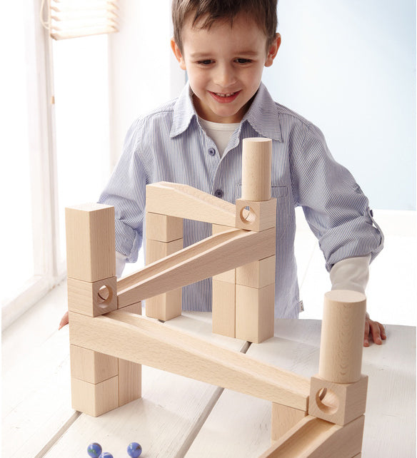 A child playing with a marble run made from different natural wooden blocks from the Haba first playing blocks 