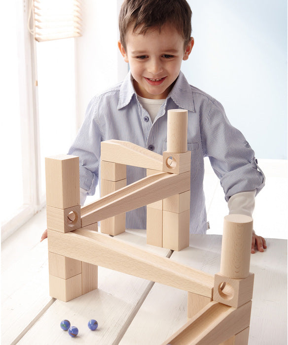 A child playing with a marble run made from different natural wooden blocks from the Haba first playing blocks 