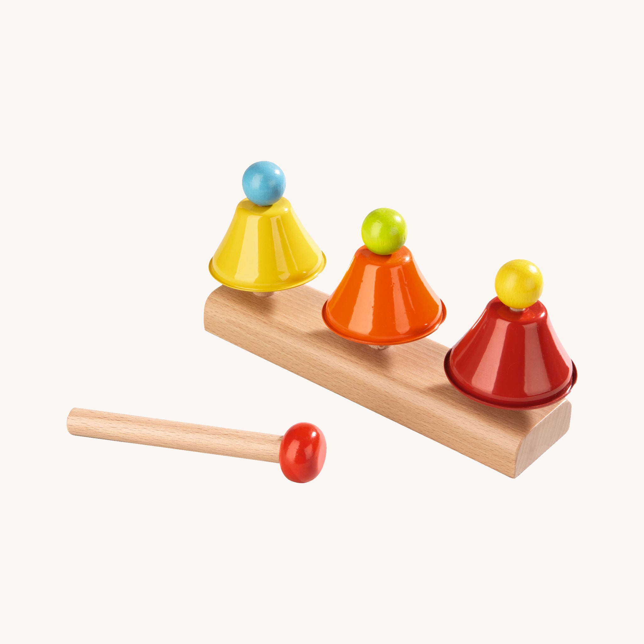 Haba Musical Glockenspiel Chimes Toy. 3 colourful metal bell chimes in yellow, orange and red set on a wooden base, with a wooden stick with a red top to create beautiful musical melodies, on a cream background