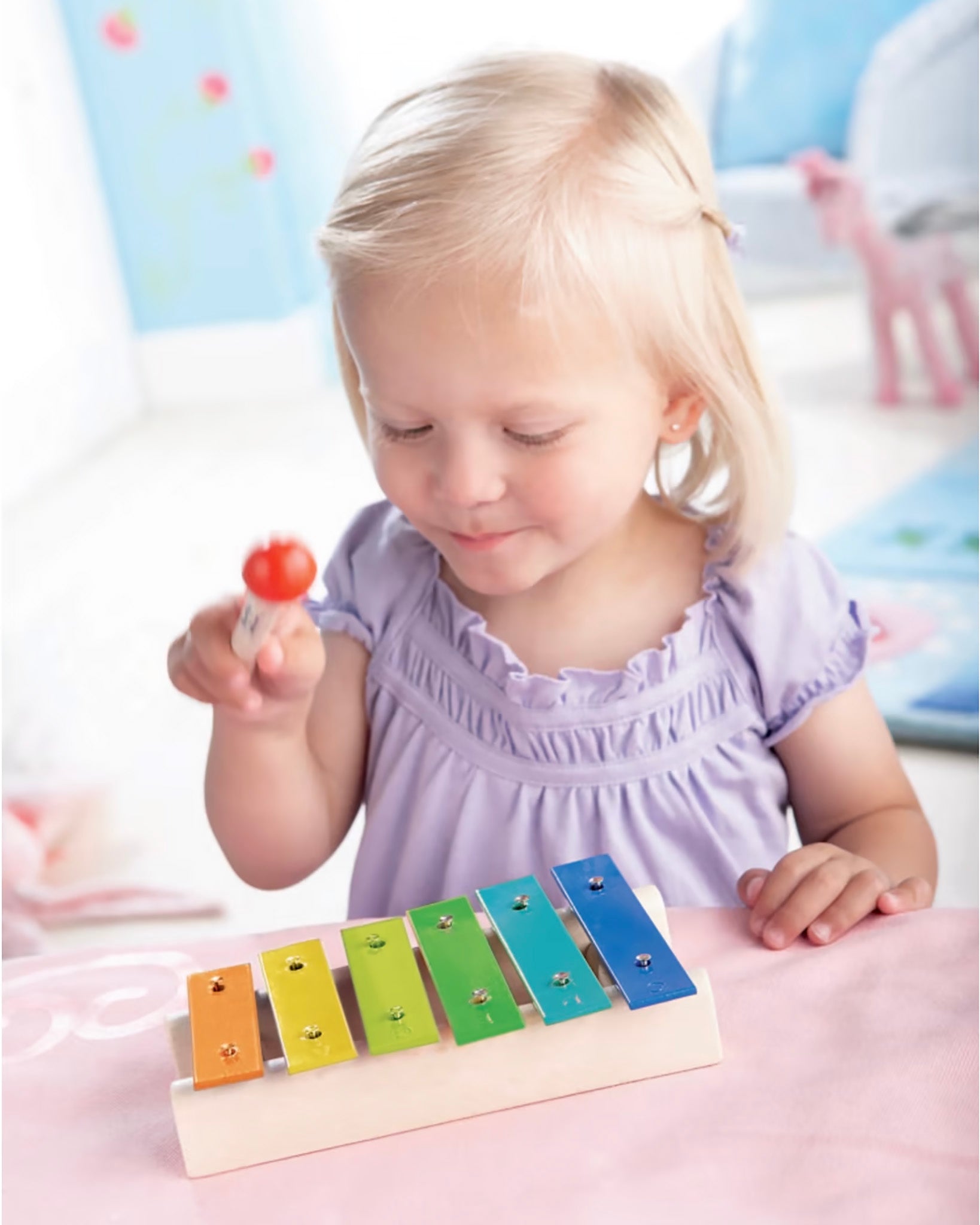  Xylophone Toy Instrument. A wooden drumming stick on top of a row of colourful flat metal bars pinned into a wooden base with each one being a different musical note