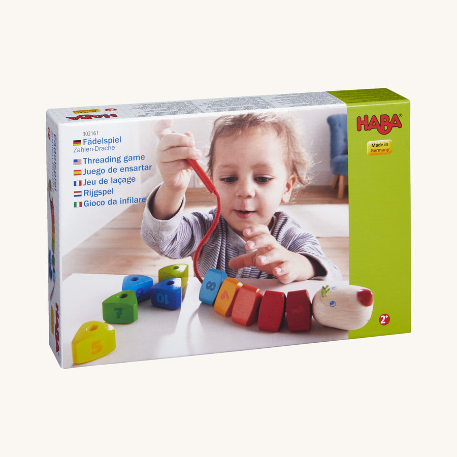 HABA Number Dragon Threading Game is made up of 10 rainbow coloured triangular wooden beads numbered 1 to 10 and a cheerful dragon's head with a cord and wooden threading needle. This image shows the triangular number beads on and off the red cord to show